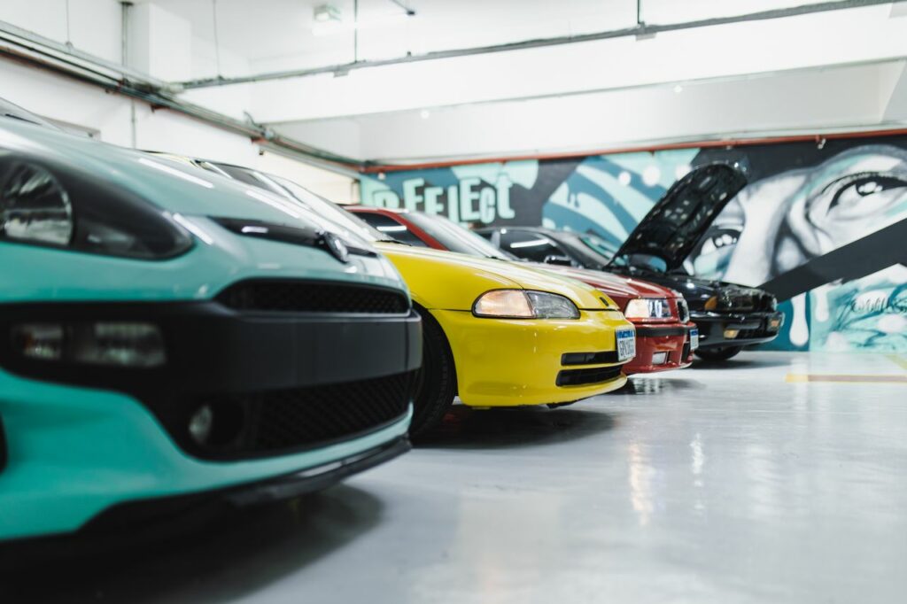 A lineup of custom sports cars showcased in a brightly illuminated garage with artistic murals.