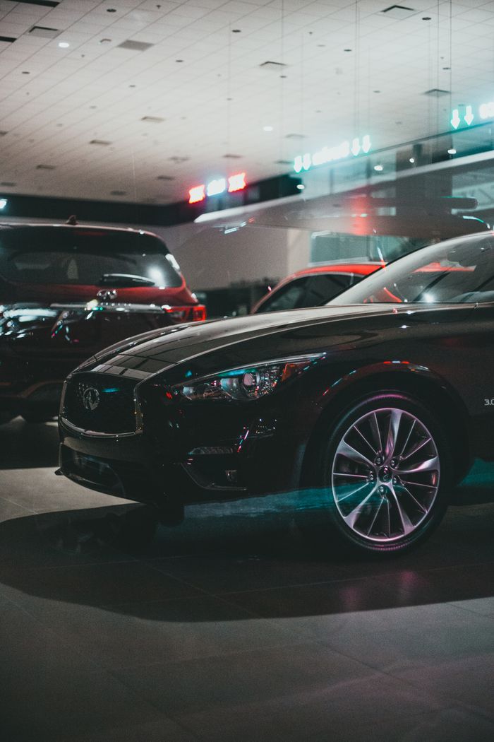 Modern polish expensive automobiles of black color placed on asphalt illuminated parking lots